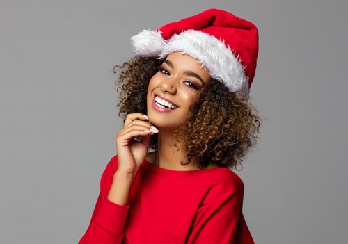 Beautiful woman in Santa hat smiling with bright, white smile from teeth whitening.